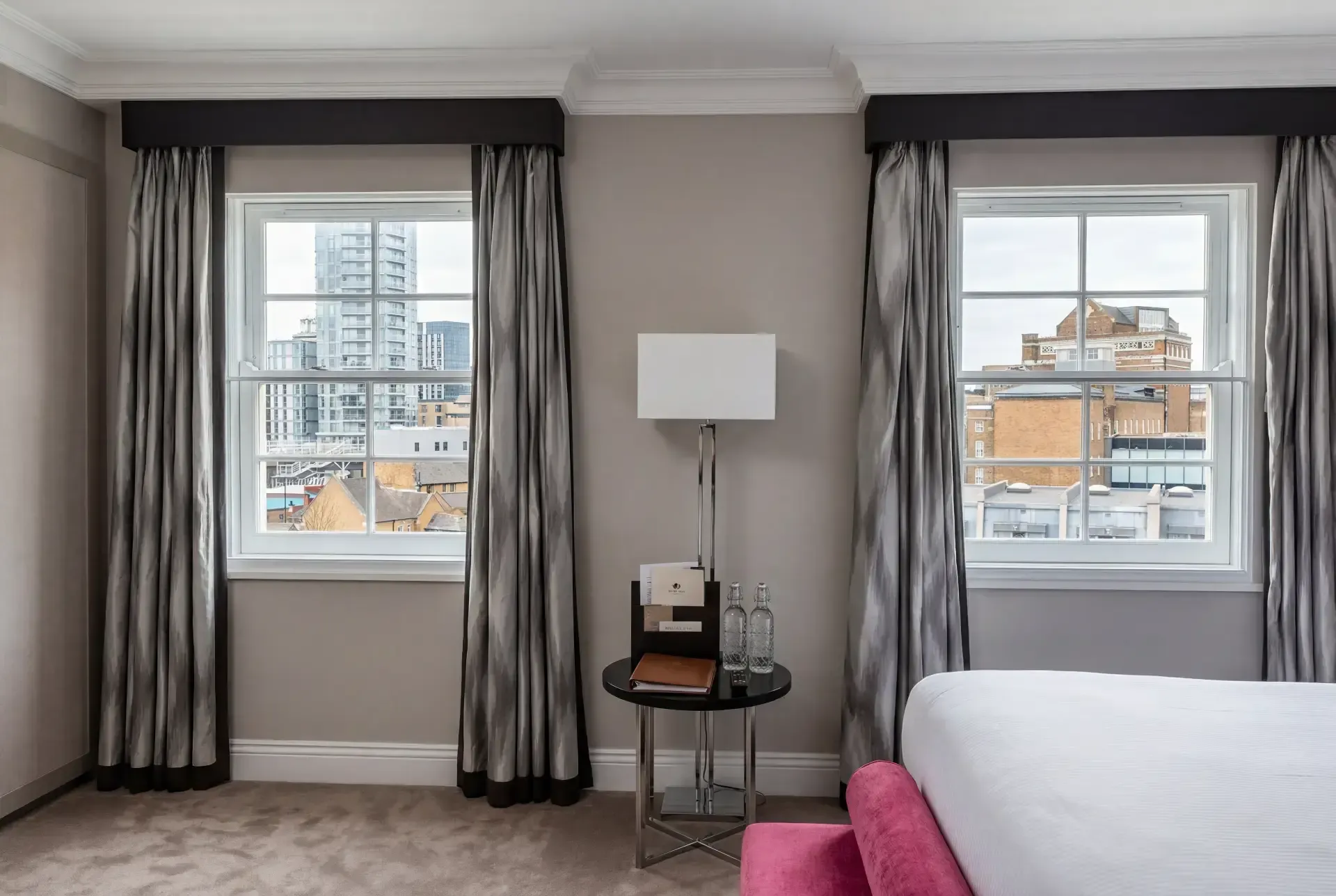 Hotel-style bedroom with two sash windows fitted with acoustic secondary glazing behind full-length curtains