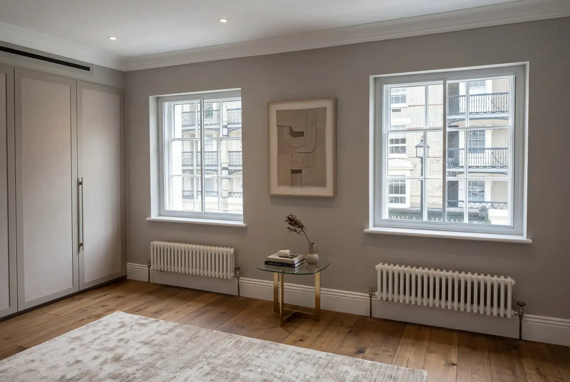 Two sash windows in a stucco-fronted London apartment fitted with discreet secondary glazing above column radiators