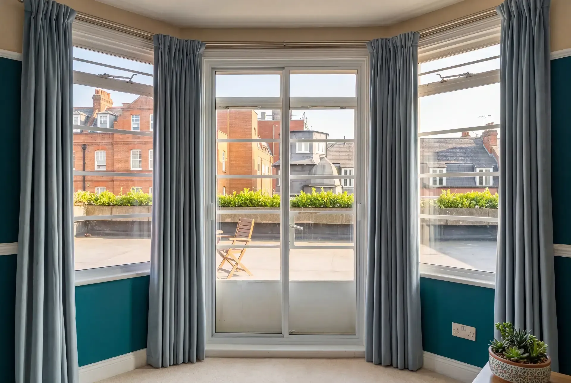 Bay window and balcony door fitted with secondary glazing, dressed with floor-length curtains in a London flat