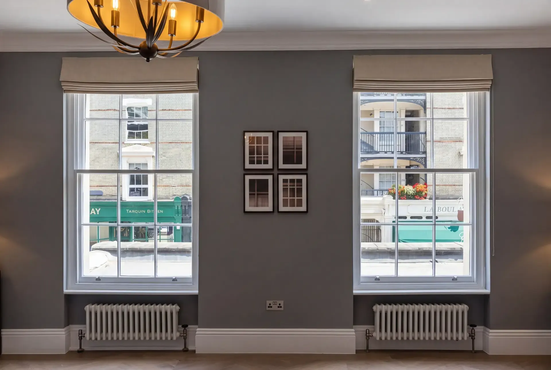Two tall Georgian sash windows facing a London high street fitted with discreet secondary glazing behind Roman blinds