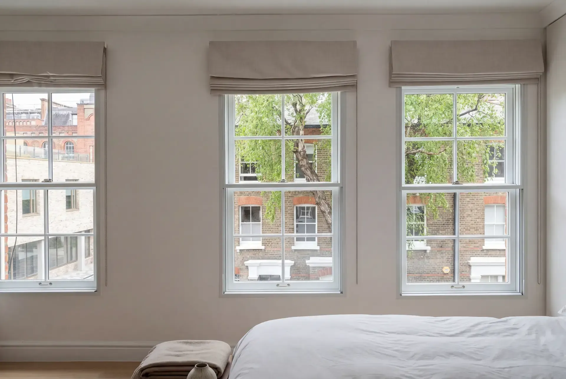 Bedroom with three sash windows fitted with slimline secondary glazing behind neutral Roman blinds