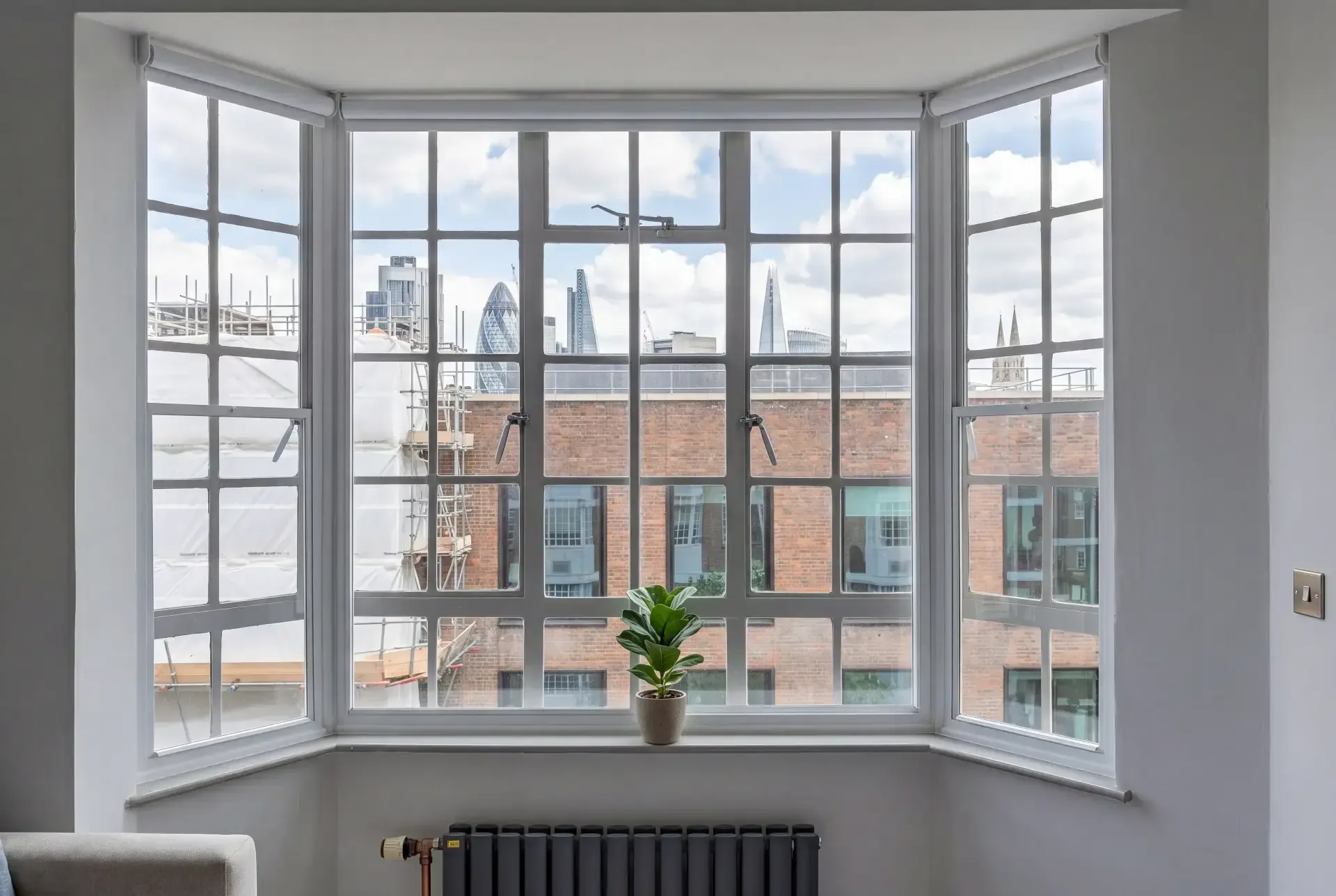 Square bay of steel-look Crittall style windows fitted with secondary glazing overlooking the City of London skyline