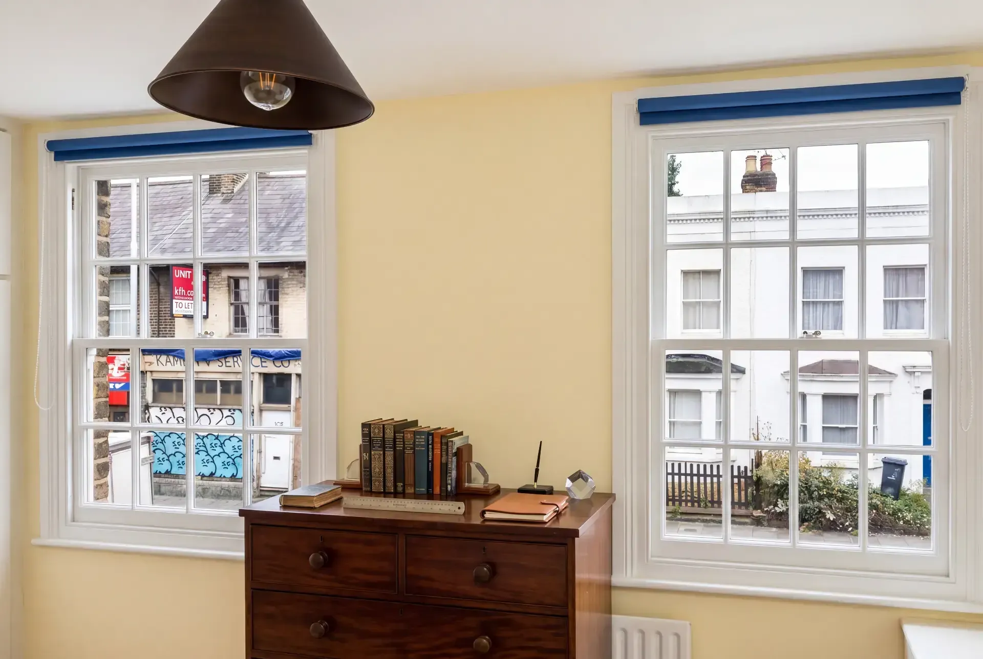 Two Georgian sash windows in a period bedroom fitted with secondary glazing above a mahogany chest of drawers