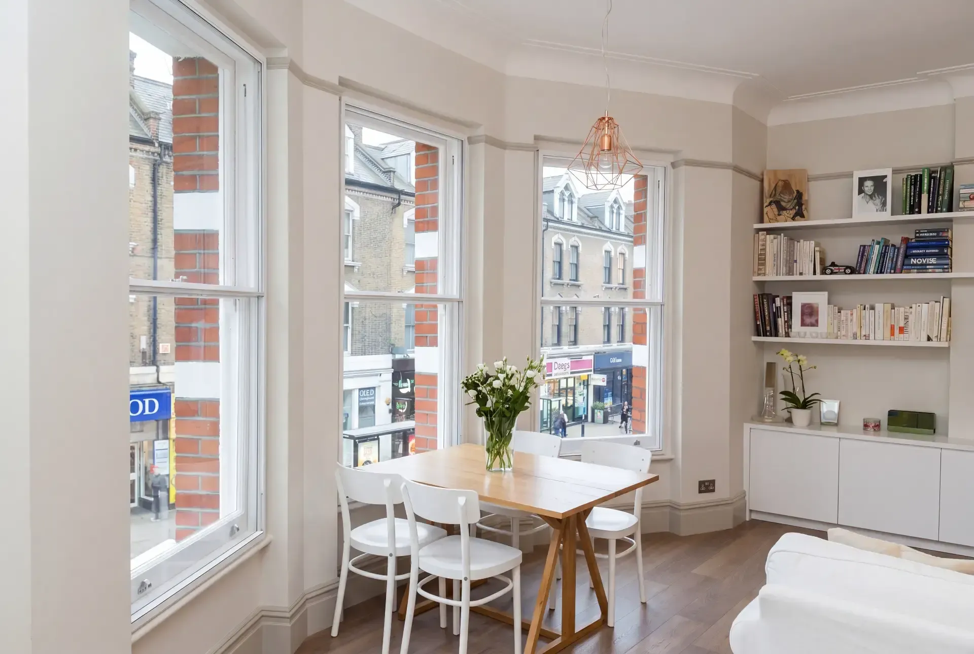 Splayed bay of three sash windows fitted with secondary glazing above a high street in a Victorian flat