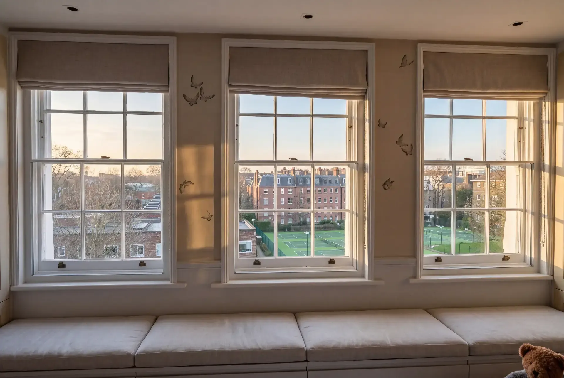 Three Georgian sash windows with glazing bars fitted with secondary glazing above a window seat