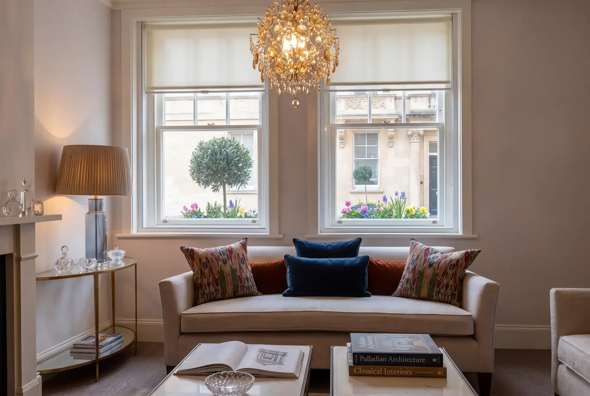Two sash windows fitted with secondary glazing in a stucco Belgravia drawing room with chandelier and roller blinds