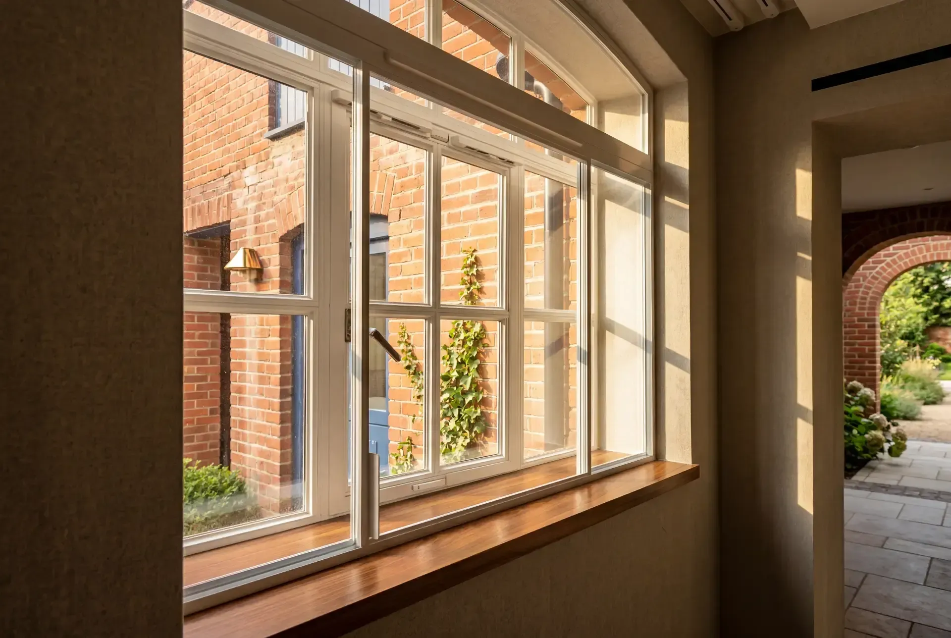 Horizontal sliding secondary glazing over a casement window with hardwood cill in a country house corridor