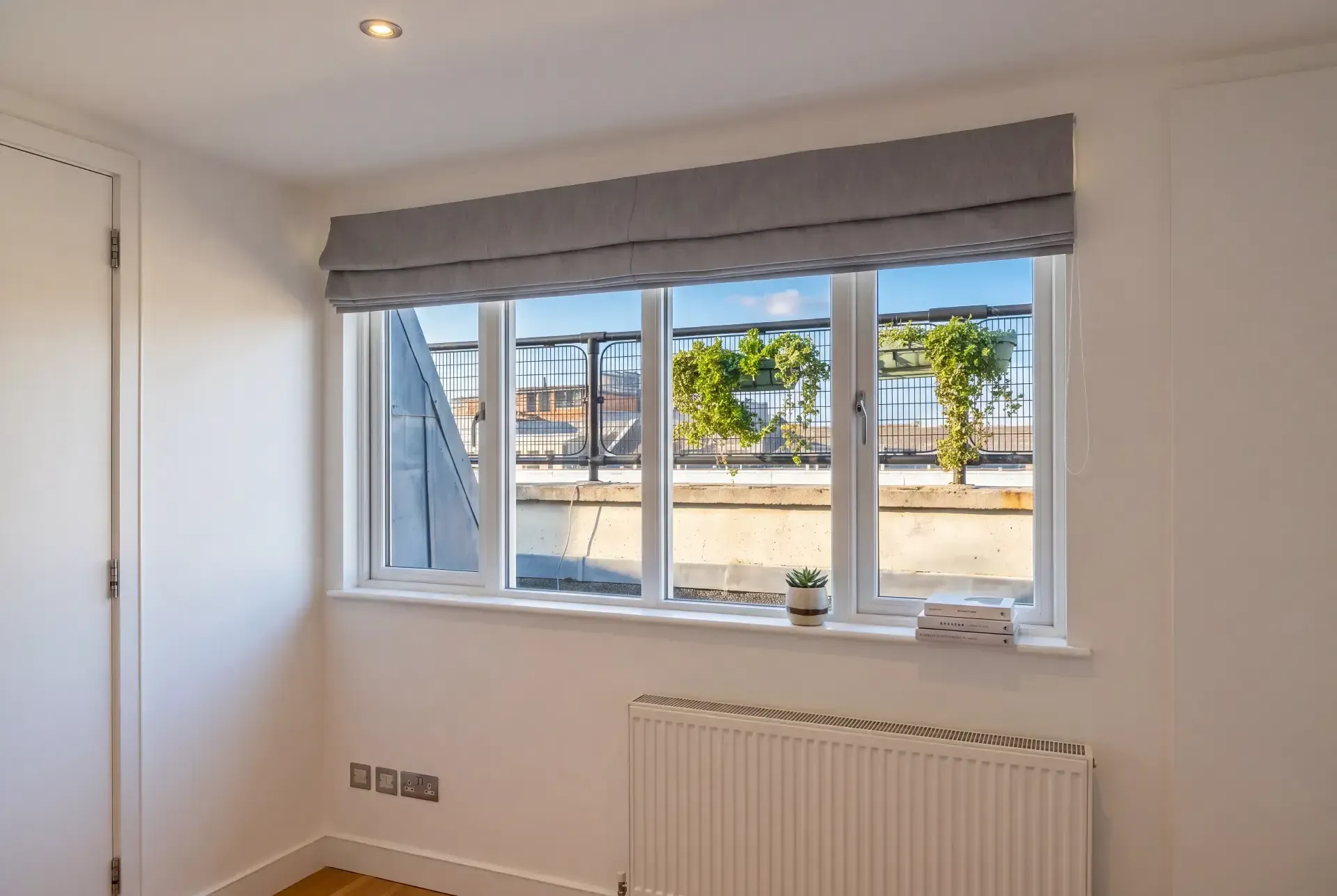 Four-pane window fitted with secondary glazing beneath a Roman blind in a roof-level flat