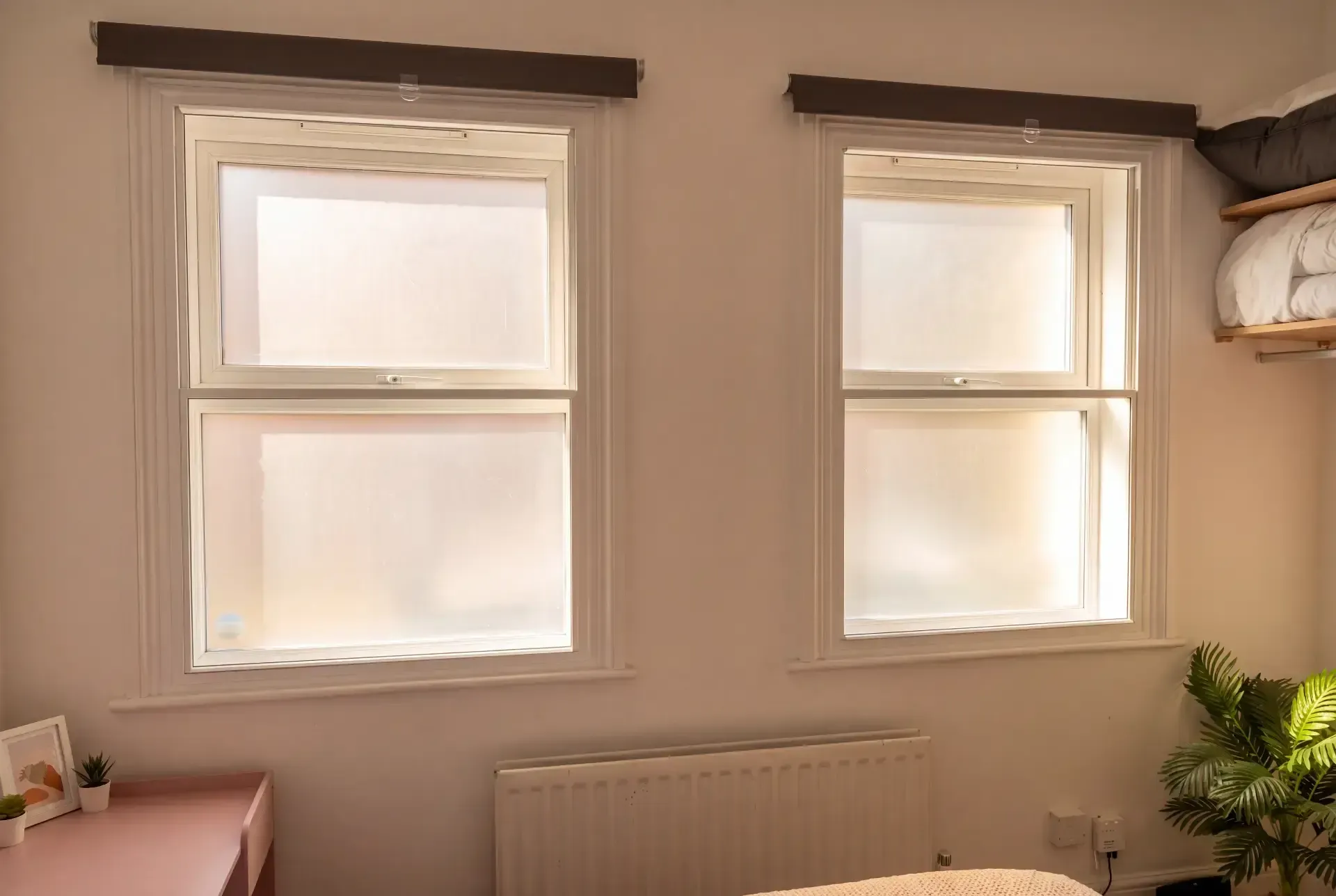 Two sash windows with secondary glazing and blackout blinds in a compact London bedroom