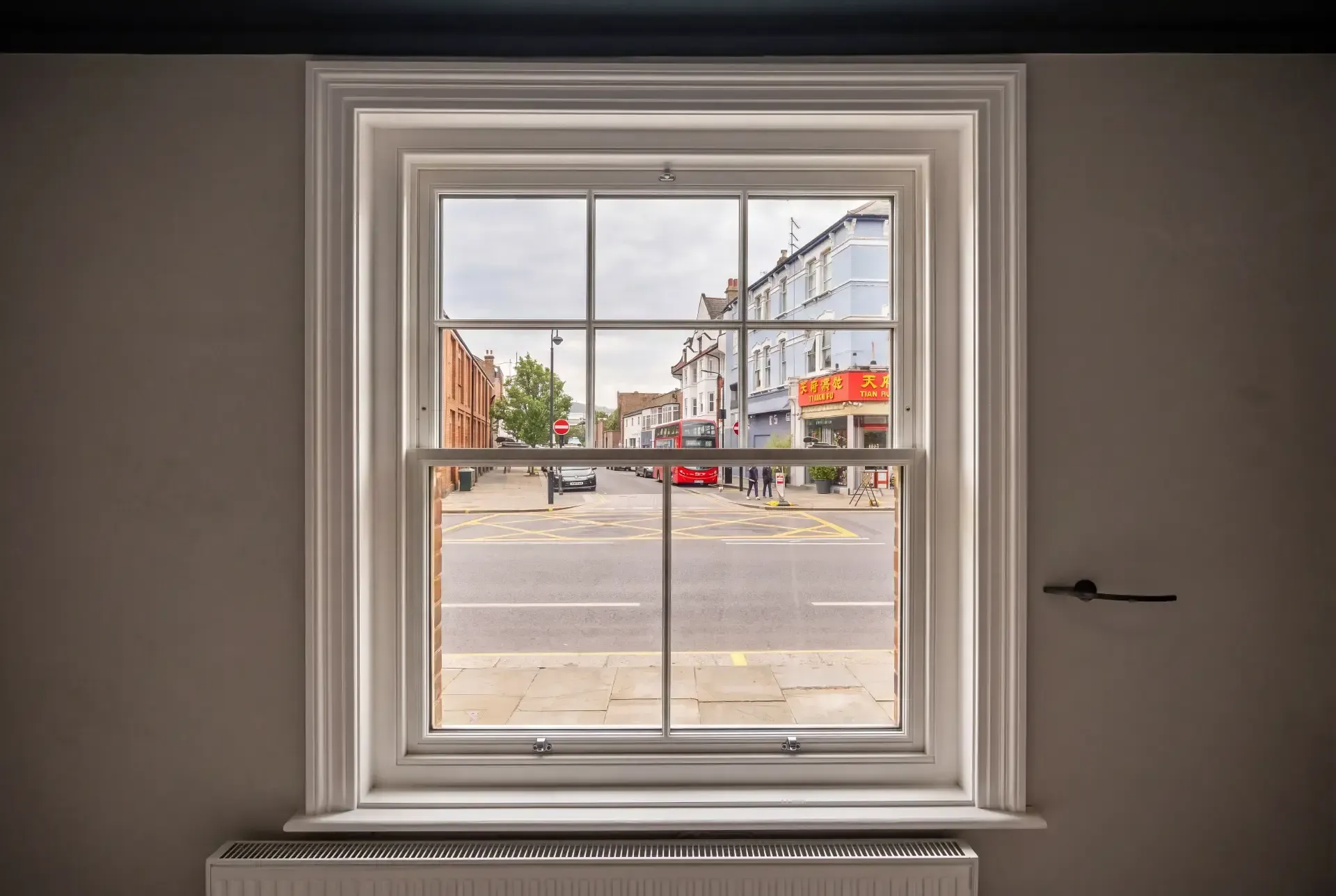 Georgian-bar sash window fitted with slimline secondary glazing overlooking a London high street with a red bus