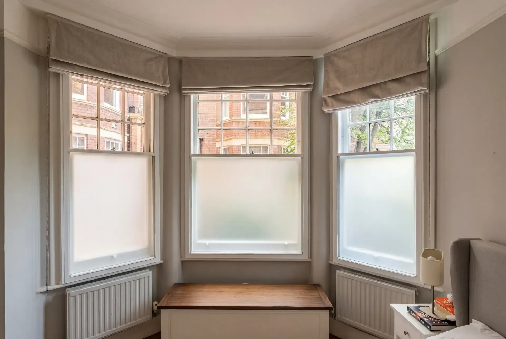 Splayed bay of three sash windows with Roman blinds and secondary glazing in a mansion block bedroom