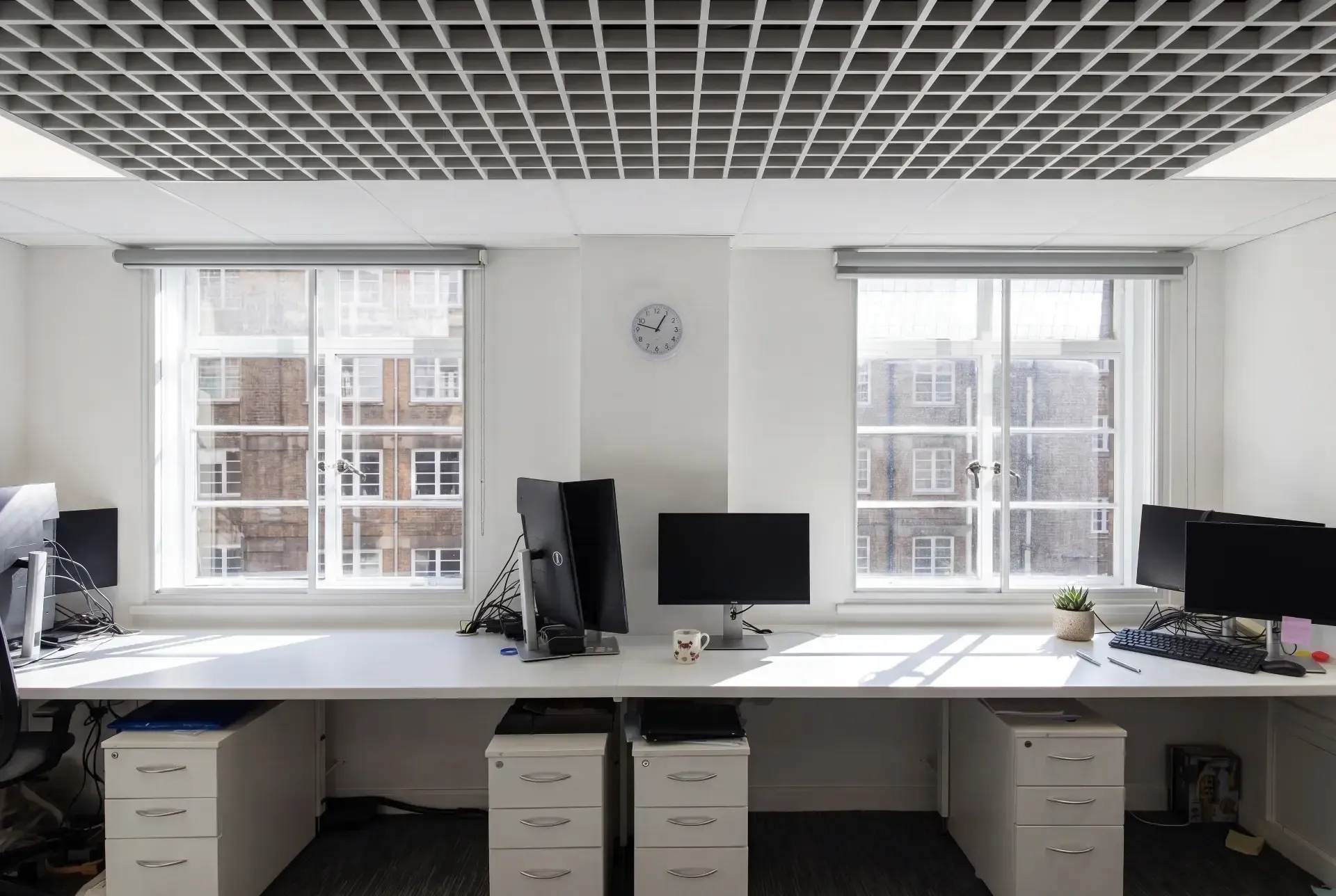 Open-plan office with two sash windows fitted with secondary glazing above a long desk run